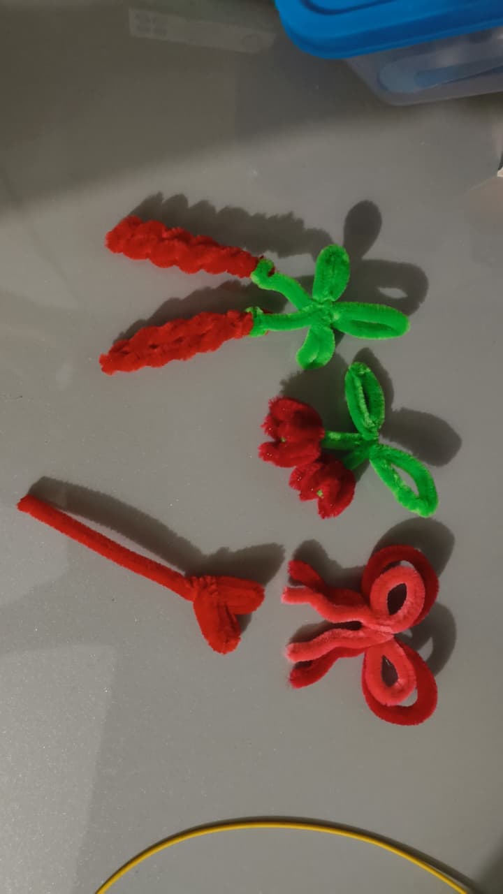 Hands shaping a red chenille flower, petals half-finished